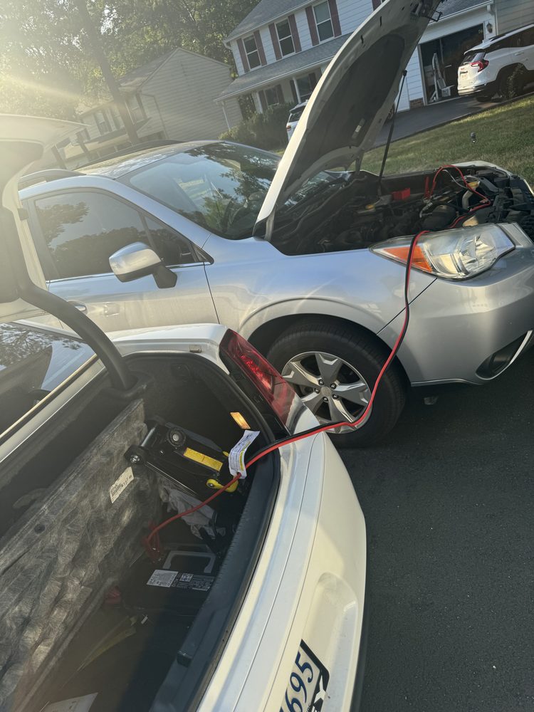 Jump start service connecting booster cables to a stalled SUV in a Richmond driveway